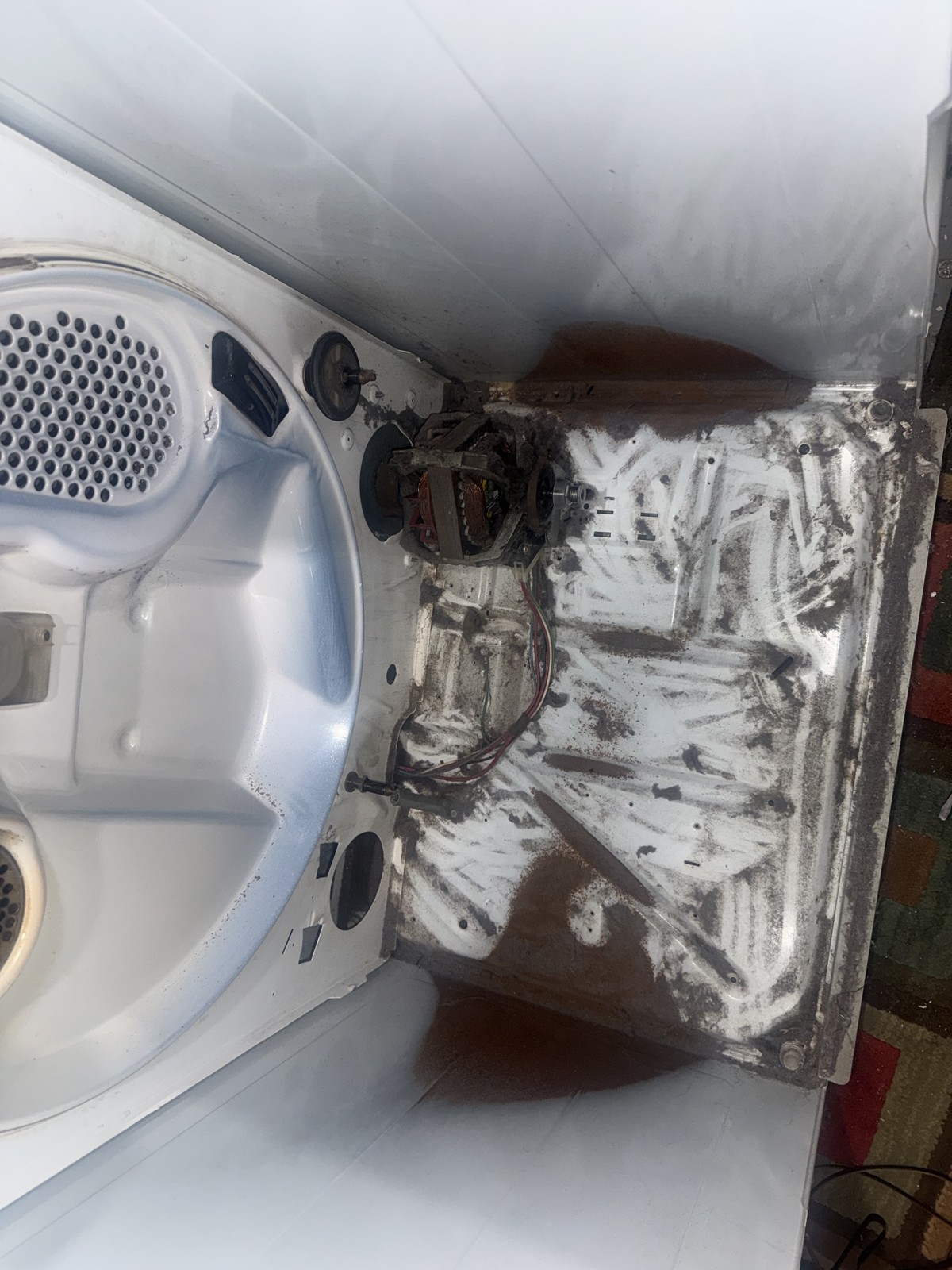 Dryer interior showing motor and base pan with accumulated lint, photographed during a deep cleaning and repair