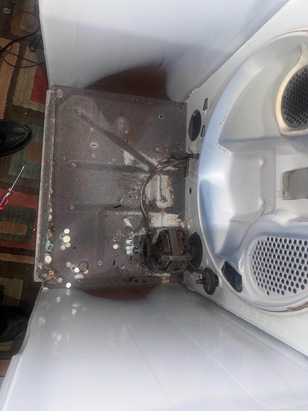 Dryer with the drum removed showing the motor mount, blower wheel, and base pan during a real repair