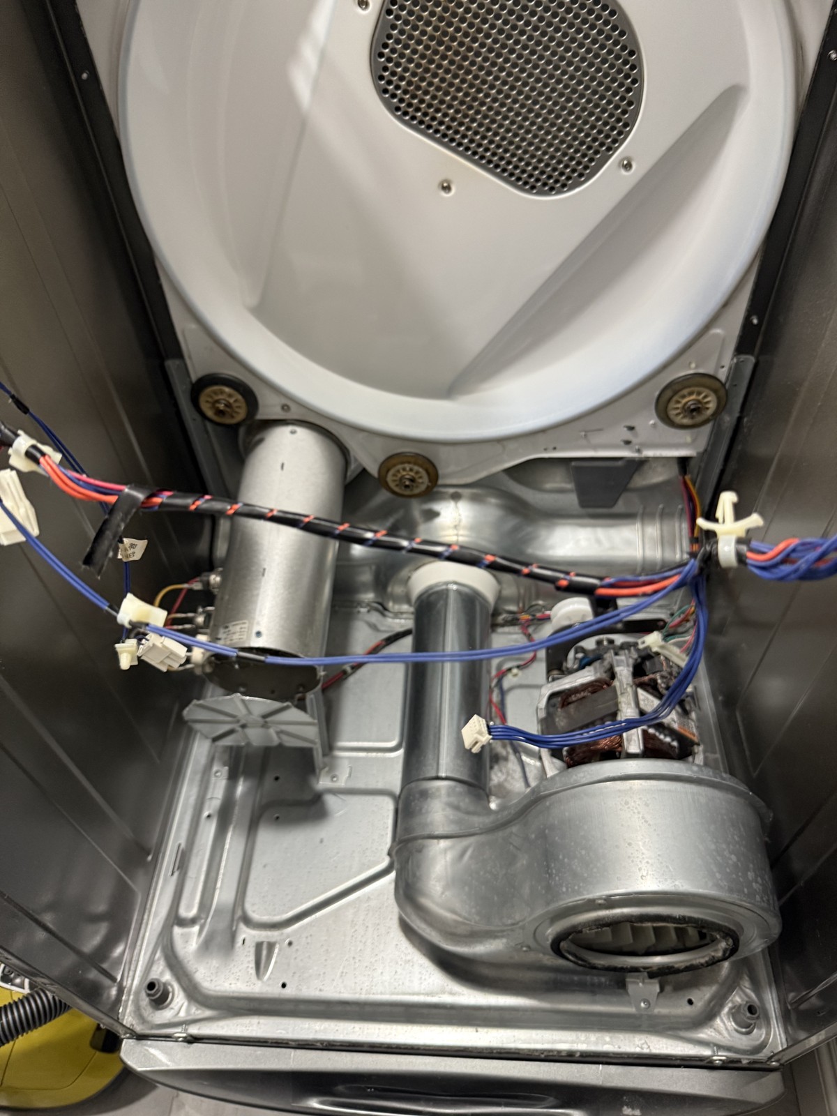 Open dryer cabinet showing the blower housing and motor area during a real appliance repair service call