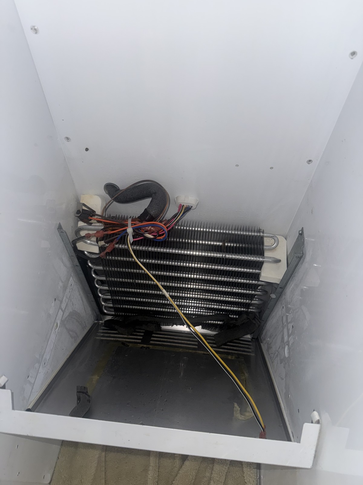 Refrigerator freezer evaporator coil and defrost heater exposed during a defrost-system diagnosis and repair