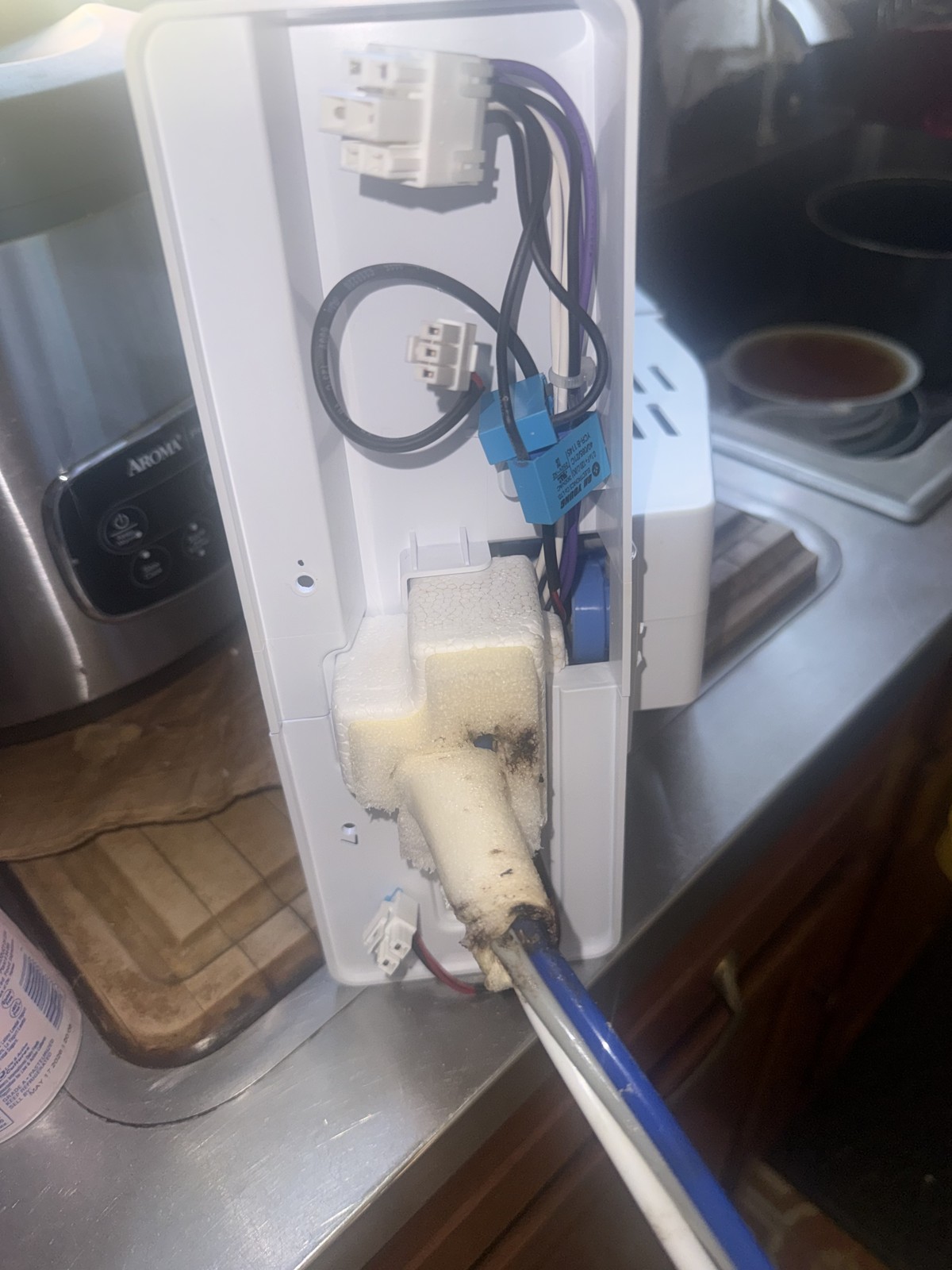 Refrigerator water and ice dispenser control housing opened on a kitchen counter during a service call