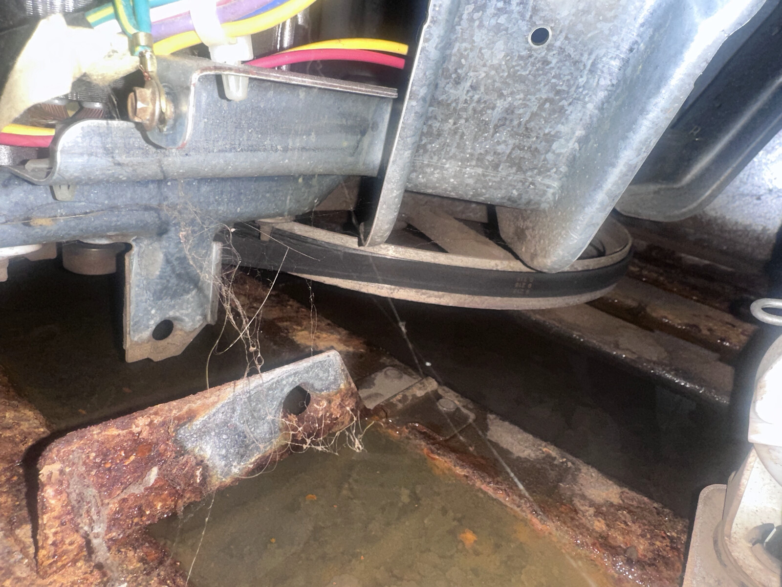 Bottom of a washer drum and transmission showing rust and old grease during a deep washer repair