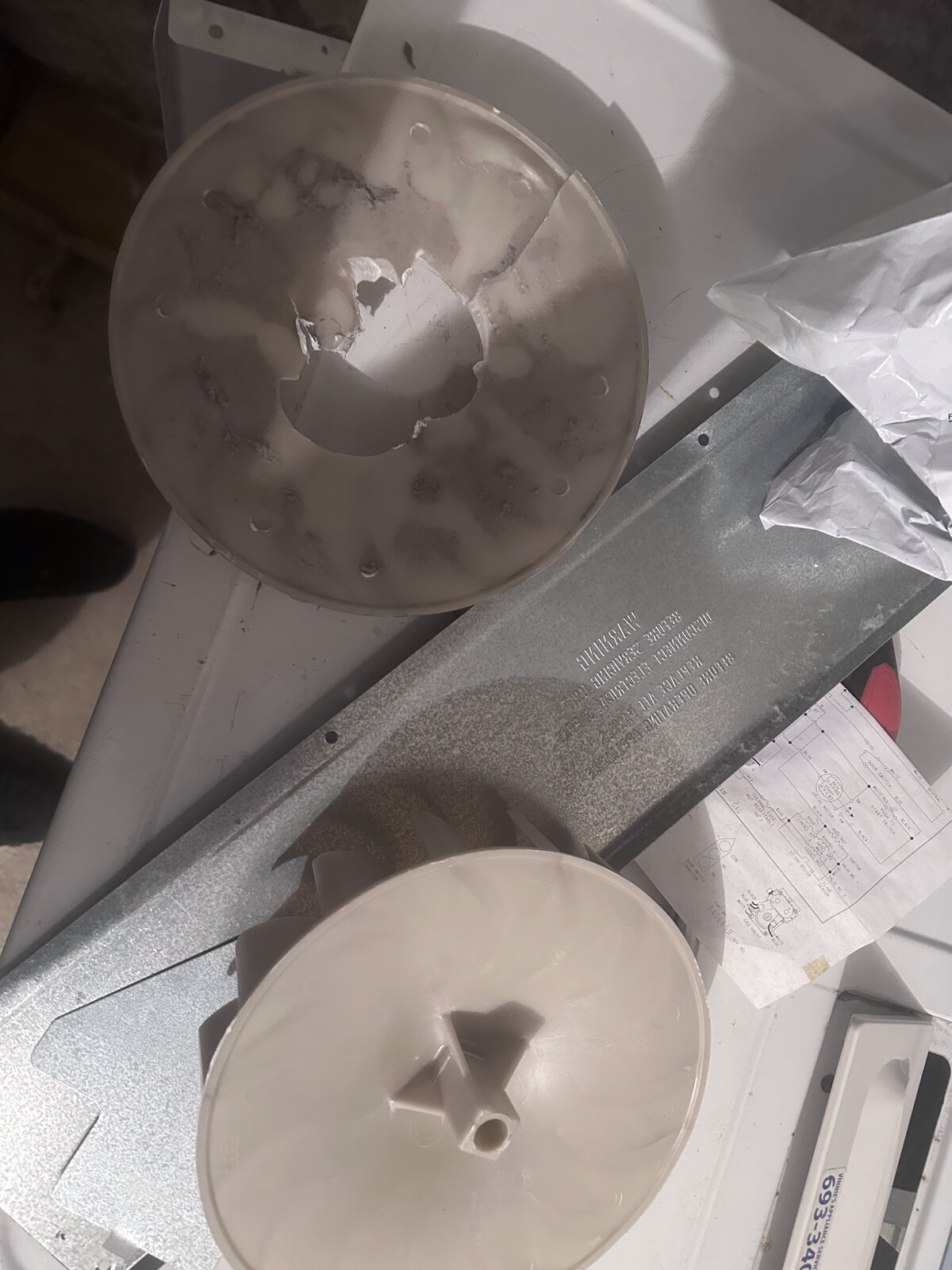 Whirlpool top-load washer wash plate and transmission components laid out on the floor during a repair